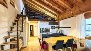 Eine moderne Küche mit einer zentralen Kochinsel, einer Holztreppe und einem Essbereich mit einem Holztisch und Stühlen.