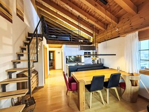 Eine moderne Küche mit einer zentralen Kochinsel, einer Holztreppe und einem Essbereich mit einem Holztisch und Stühlen.