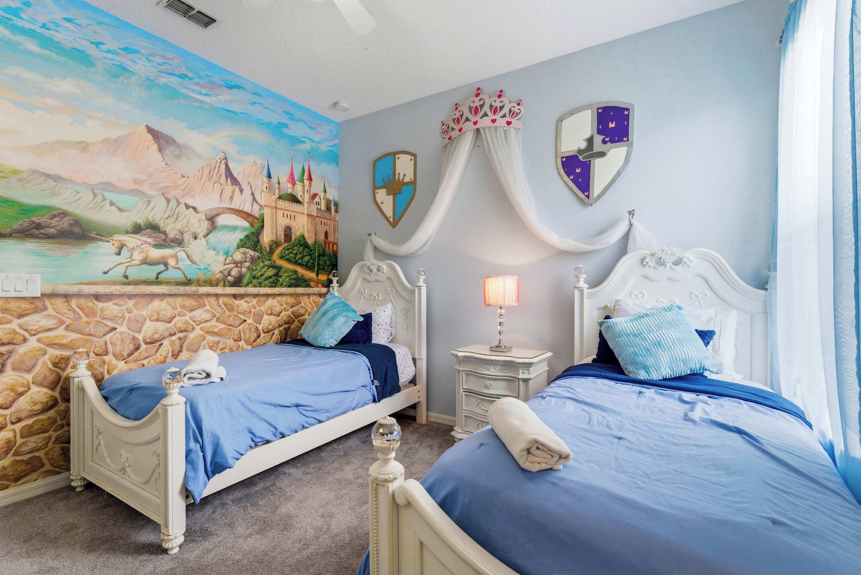 Un dormitorio con dos camas, una pared de piedra, un mural y una mesita de noche con lámpara.