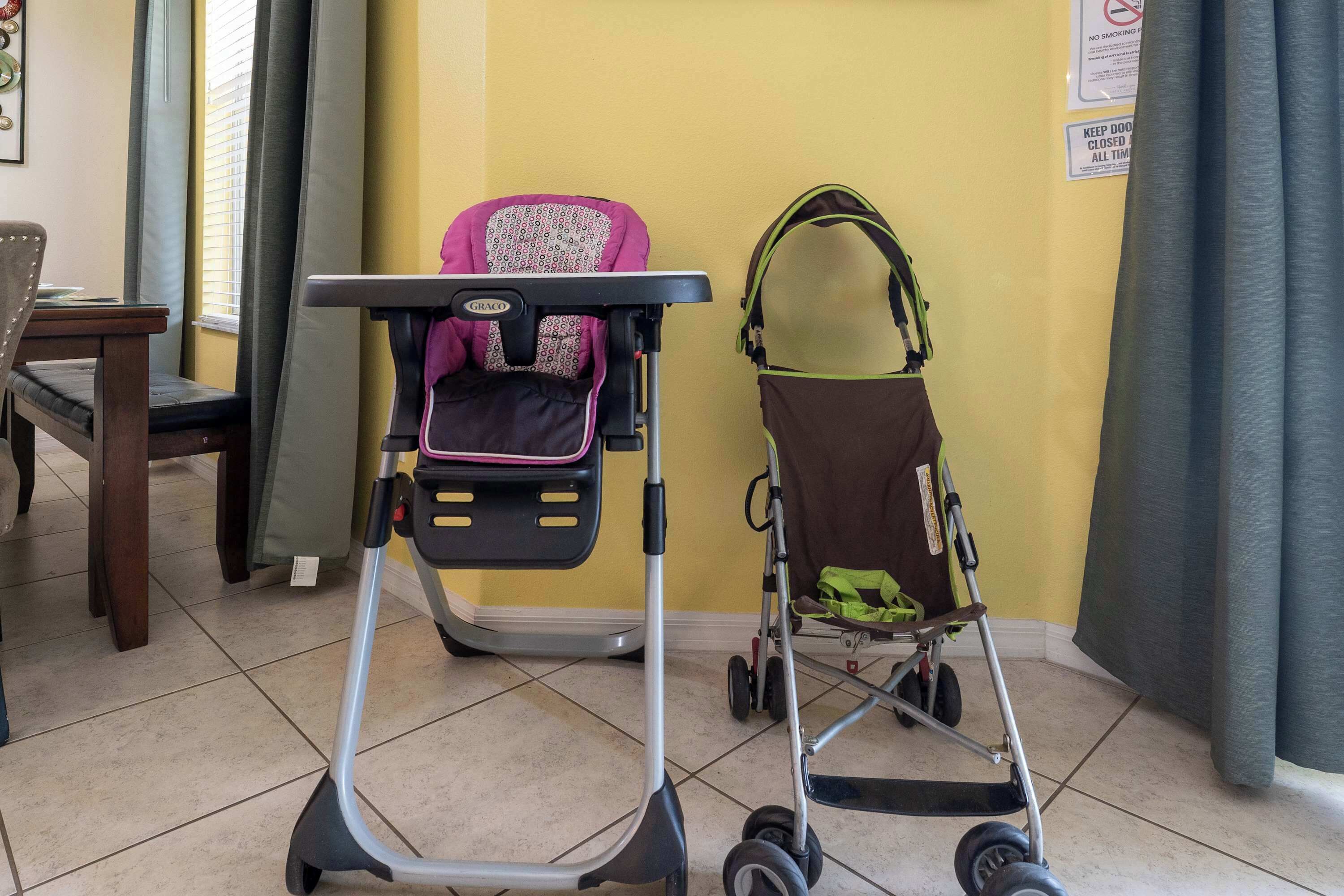 A room with a baby stroller, a dining table, and a chair.