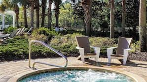 Un bain à remous entouré de chaises longues et bordé d’une terrasse en briques.