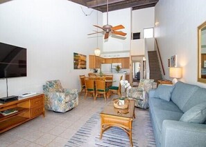 A living room with a sofa, coffee table, TV, and a ceiling fan. - Island Retreat - Two bedroom Two bathroom Hale Kamaole 329 (Kihei)