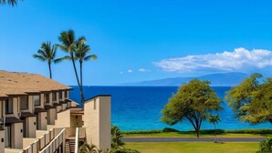 A hotel with a view of the ocean, palm trees, and a clear sky. - Island Retreat - Two bedroom Two bathroom Hale Kamaole 329 (Kihei)