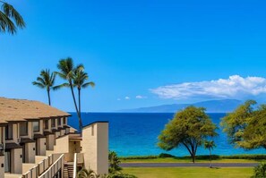 A hotel with a view of the ocean, palm trees, and a clear sky. - Island Retreat - Two bedroom Two bathroom Hale Kamaole 329 (Kihei)