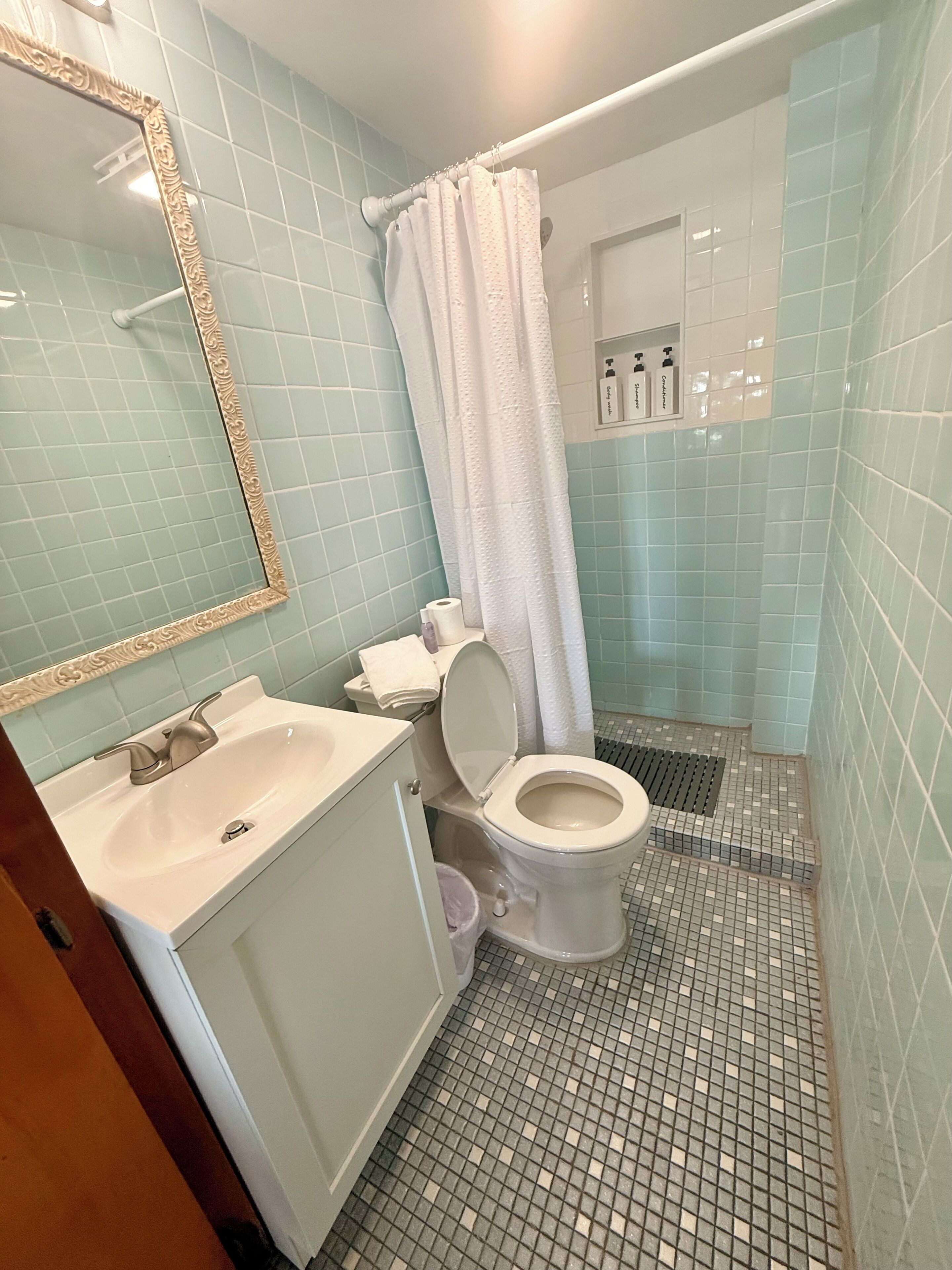 Une salle de bain comprenant un lavabo, des toilettes et un espace douche.