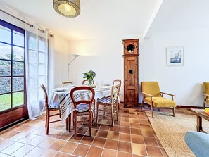 A dining area with a table set for four, a tall wooden clock, and a chair with a yellow cushion. - La littorine by Interhome (Quiberon)