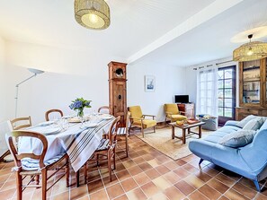 Zona pranzo con tavolo imbandito per quattro persone, una sveglia e una televisione nel soggiorno.