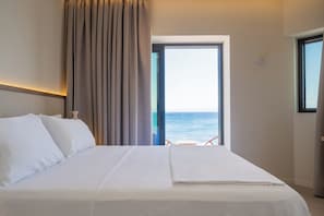 Una habitación de hotel con cama, vista al mar y balcón.
