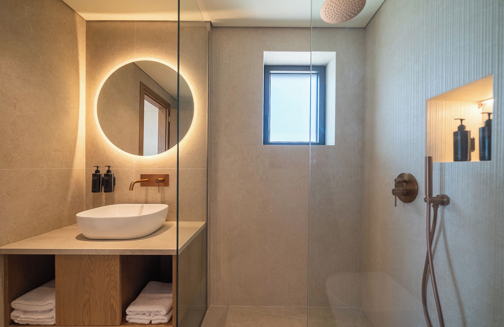Un bagno moderno con uno specchio rotondo, un lavabo incassato e una cabina doccia.