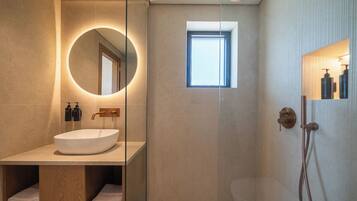 Un bagno moderno con uno specchio rotondo, un lavabo incassato e una cabina doccia.