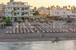 A beachside hotel with multiple lounge areas, umbrellas, and a view of the sea. - The Palms Kos  (Kos)