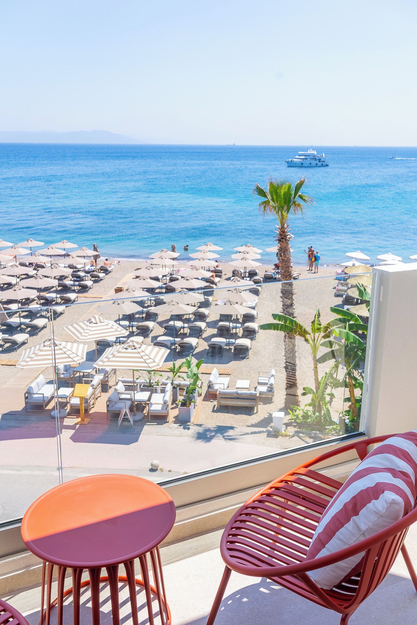 A balcony with a view of a beach with umbrellas and lounge chairs.