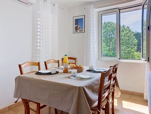 A dining area with a table set for four, a bottle of orange juice, bread, and a cup. - Sainte Marguerite by Interhome (Saint-Tropez)