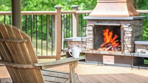 Eine Holzterrasse mit einem Grill aus Stein und einer weißen Tasse auf einem Tisch.