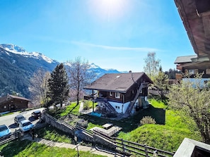 Ein Haus mit Balkon, einer Holzterrasse und Bergblick.