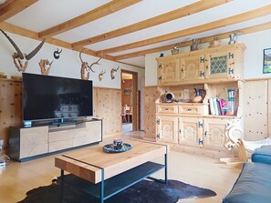 Ein Wohnzimmer mit Fernseher, Holzschränken und Geweih-Dekorationen.