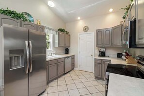 A modern kitchen with stainless steel appliances, grey cabinetry, and a tiled floor. - Norris Lake House W Private Boat Slip & Game Room (LaFollette)