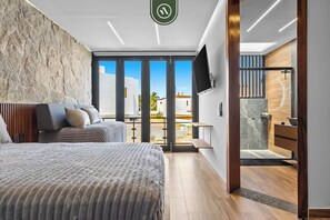 Ein modernes Schlafzimmer mit einem großen Bett, einem Fernseher und Blick ins Freie.