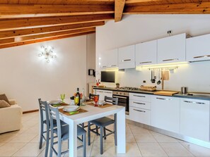 Eine moderne Küche mit weißen Schränken, einem Esstisch mit Stühlen und einer Holzbalkendecke.