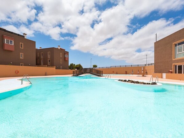 Piscina com uma ponte, cercada por edifícios.
