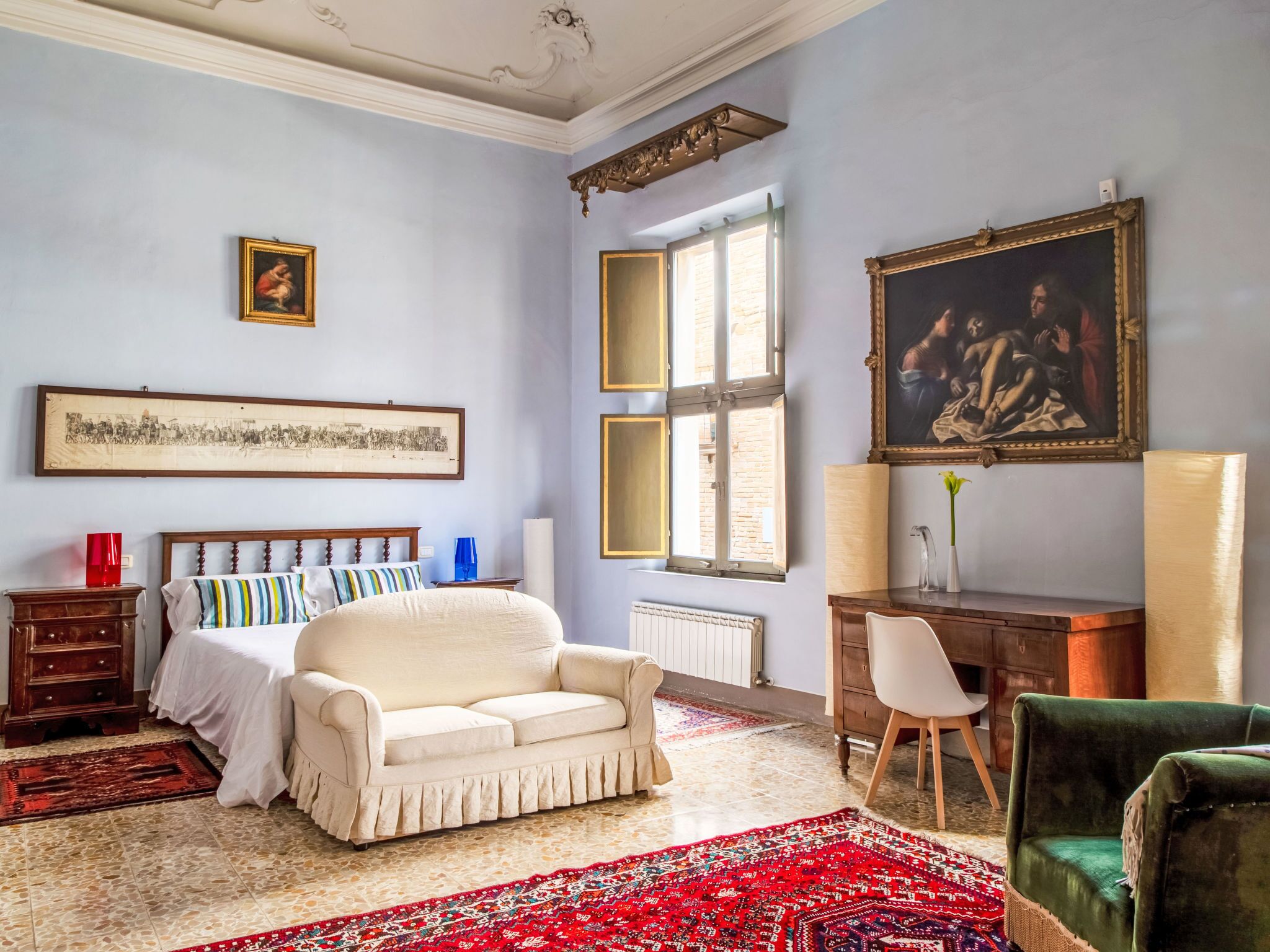 Ein Zimmer mit Bett, Schreibtisch, Stuhl, Heizkörper und einem Fenster mit Blick.