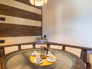 A round table with a glass top, surrounded by wooden chairs, a coffee maker, and white cups and saucers. - Baita del Sole by Interhome (Bormio)