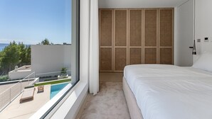 Une chambre avec une grande fenêtre, un lit, une vue sur la piscine et un balcon.