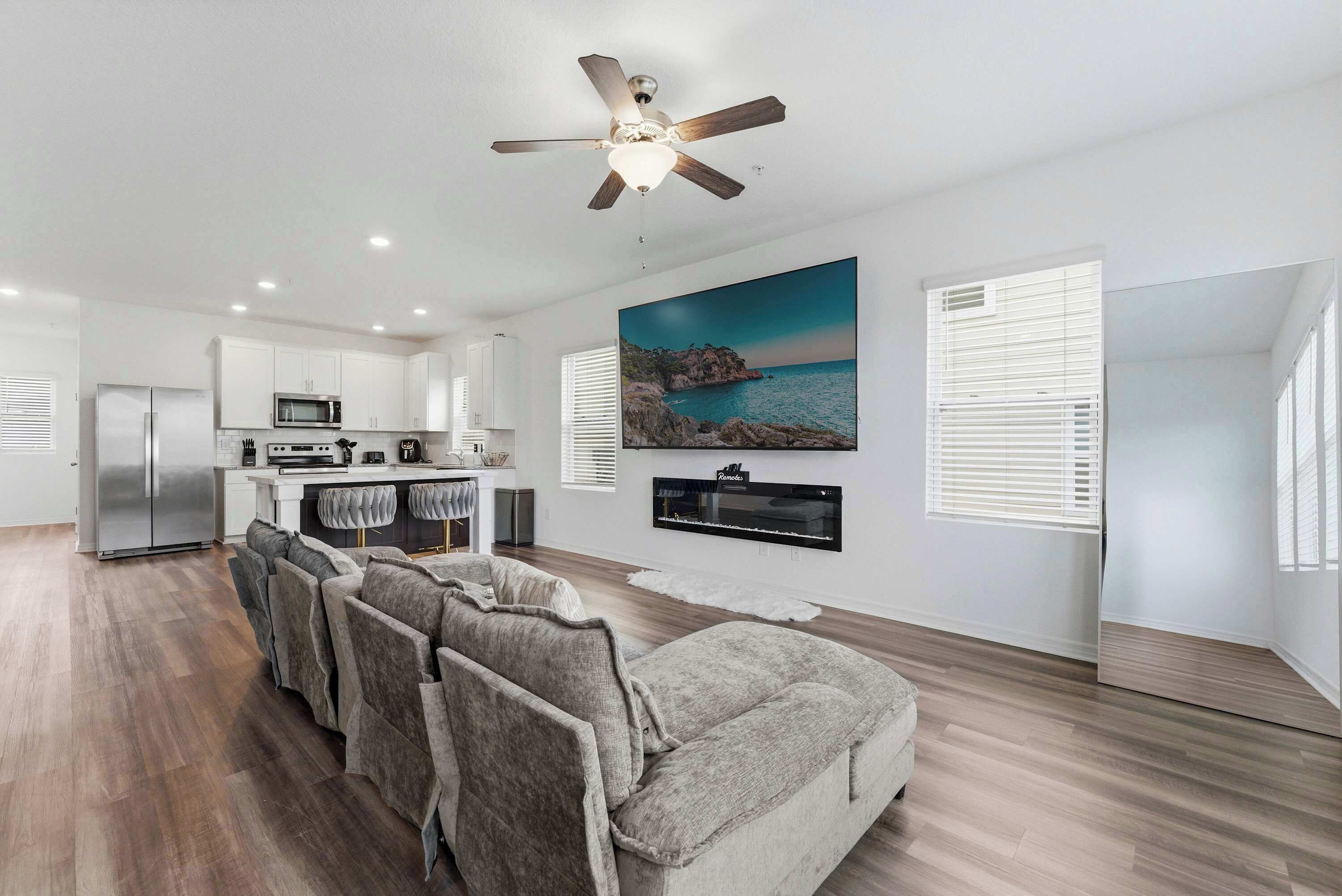 A modern kitchen with white cabinets, a built-in microwave, and a dining area with a sofa and chairs.