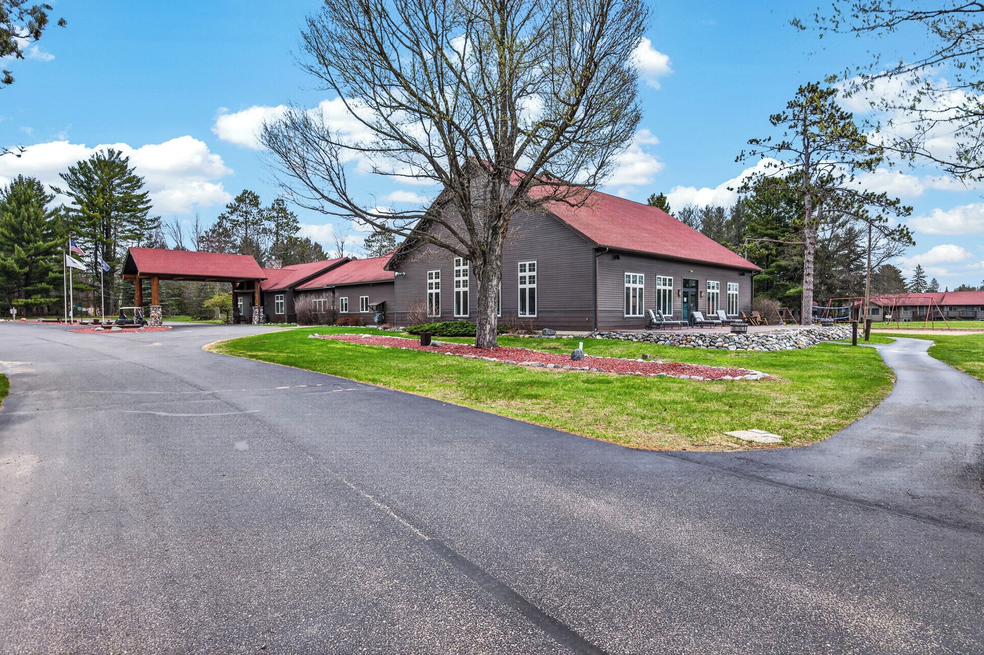 A residential building with a red roof, multiple windows, and a well-maintained lawn.