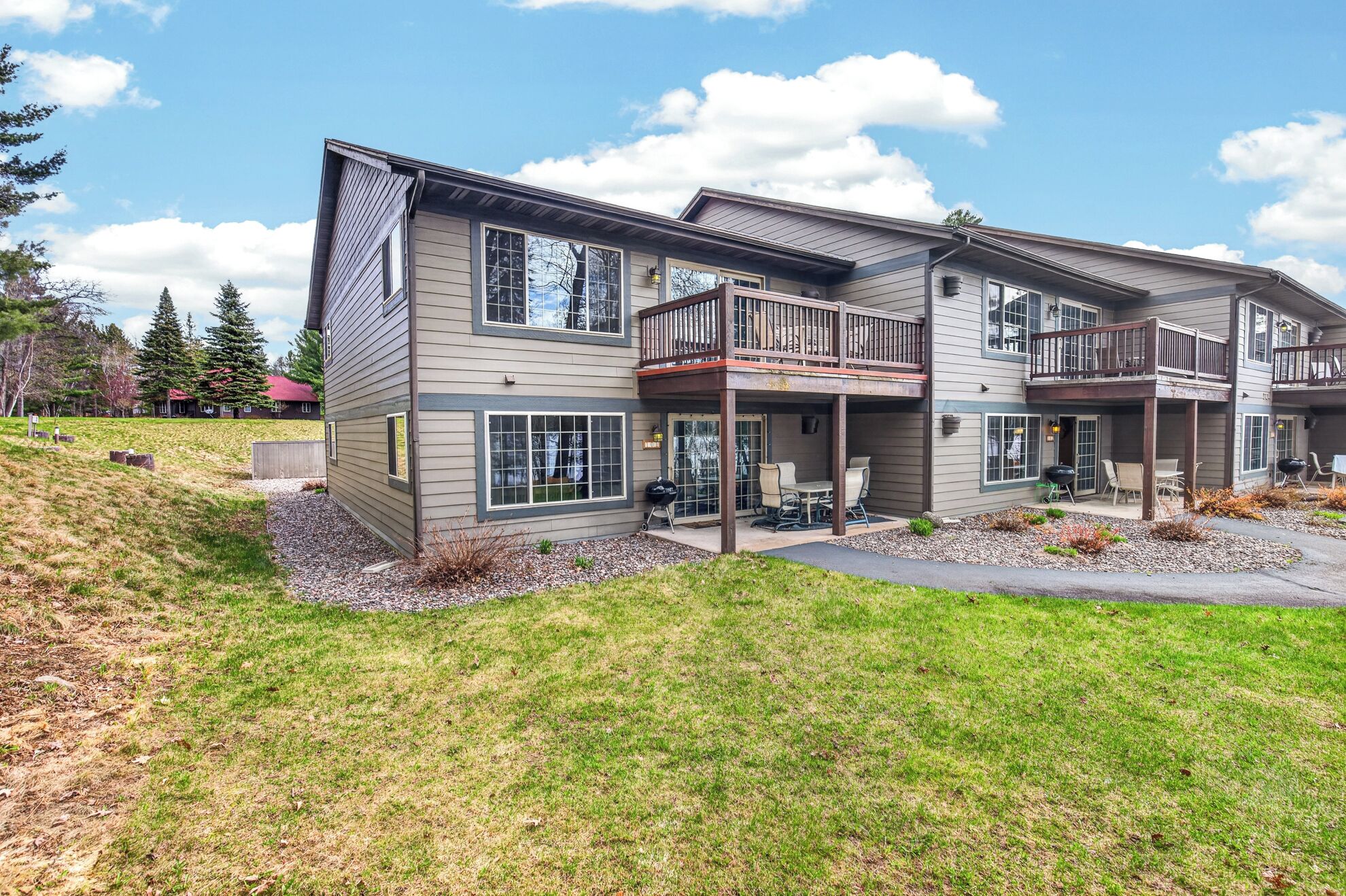 A two-story residential building with a covered patio area, large windows, and a visible deck.