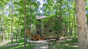 A two-story cabin with a wooden deck and a staircase, surrounded by trees. - Modern Tyrolean Chalet Walk to Pool, Kayaks (Innsbrook)