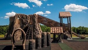 Un parque infantil con una estructura de madera para escalar y un tobogán.