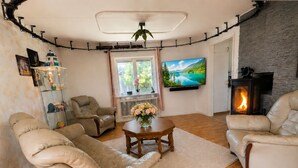 Un salón con sofás de cuero, una mesa de centro de madera, chimenea, televisor y ventana con vista al lago.