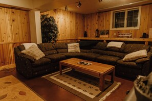 A cozy living room with a sectional sofa, a coffee table, and a large plant.