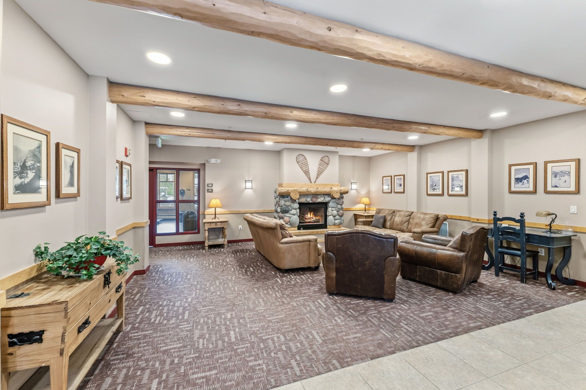 A spacious living area with a fireplace, multiple sofas, a wooden bench, and framed pictures on the walls.