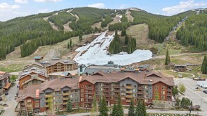 A lodge with multiple floors, a ski slope in the background, and a mountainous landscape. - Copper Mountain Center Village Condo | Halfpipe Views, Walk to Lifts (Frisco)