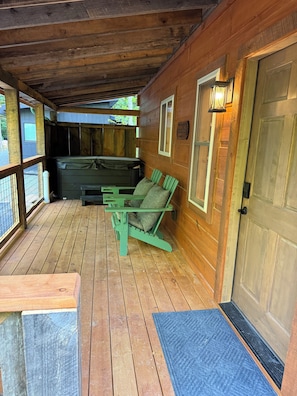 Eine Holzterrasse mit Whirlpool, Bank und einer Tür.