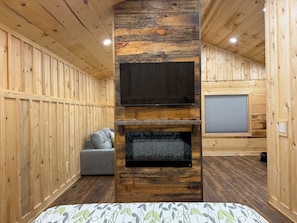 Ein Zimmer mit Holzwänden, einem Kamin, einer Couch und einem Fernseher.