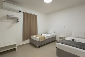 A hotel room with a bed, a bedside table, a small bedside table, a wall-mounted air conditioner, and a curtain. - Aconchego Cotoxó (São Paulo)