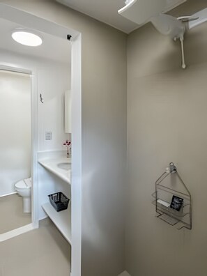 Un bany amb vàter, un lavabo, un mirall i una dutxa.