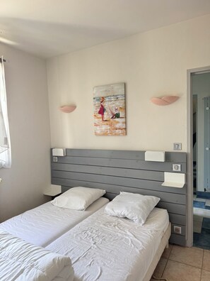 A bedroom with a bed, two bedside tables, a headboard, and a painting on the wall. - The Lighthouse Villa (Saint-Denis-d'Oléron)