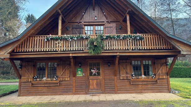 Een houten chalet met een balkon, een voordeur en een bordje met de tekst 'Gite'.