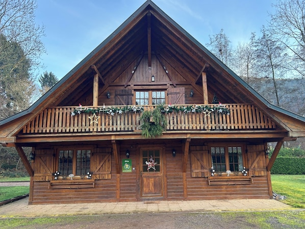 Une cabane en bois dotée d’un balcon, d’une porte d’entrée et d’une enseigne indiquant « Gîte ».