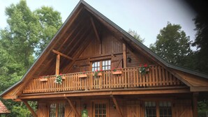 Een houten chalet met balkon, ramen en een deur.