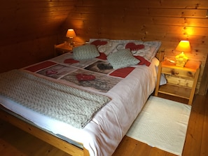 Une chambre dans une cabane en bois, avec un lit, deux lampes de chevet, une table de chevet et une couverture.