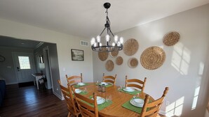 Una sala da pranzo con un tavolo rotondo in legno, sei sedie e un lampadario.
