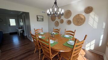 Une salle à manger avec une table ronde en bois, six chaises et un lustre.