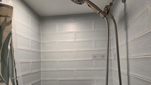 A bathroom with grey tiled walls, a showerhead, and a visible electrical outlet. - 2 Bedroom Condo Less Than A Mile To Rehoboth & Dewey Beaches (Rehoboth Beach)