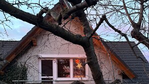 Uma casa com telhado inclinado, uma janela visível com decoração em estrela e uma escadaria que leva à entrada.