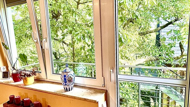Quarto com radiador, janela com vista para o verde e uma mesa com um bolo.